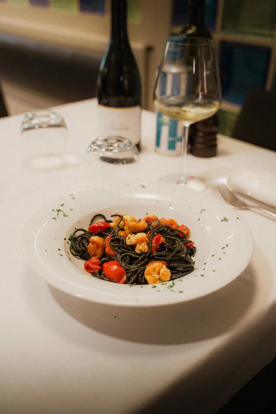 Spaghetti al nero di seppia con gamberi e pomodorini, serviti in tavola