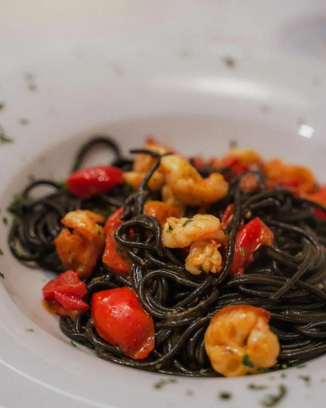 Primo piano degli spaghetti al nero di seppia con gamberi e pomodorini