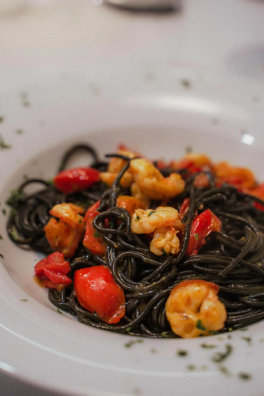 Primo piano degli spaghetti al nero di seppia con gamberi e pomodorini